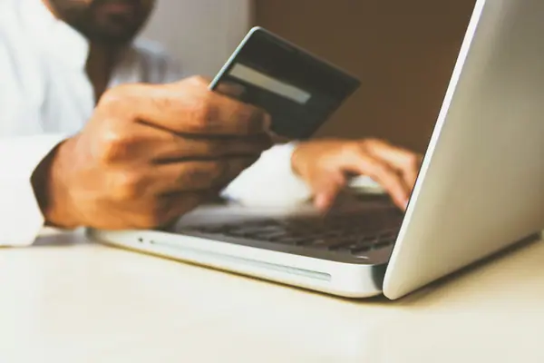 Person holding a credit card next to a laptop — custom website checkout flow